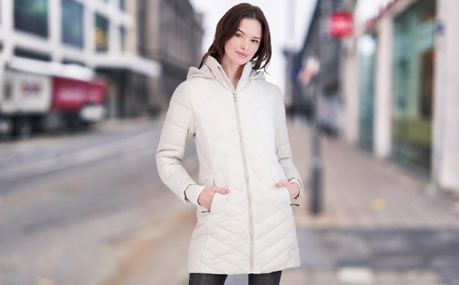 A Person is Wearing Spyder Womens Boundless Long Puffer Coat in Moonbeam Color