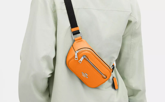 A Woman Wearing Coach Outlet Mini Belt Bag in Bright Mandarin