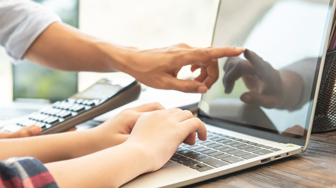 A Woman Working on a Laptop in the Office with a Coworker