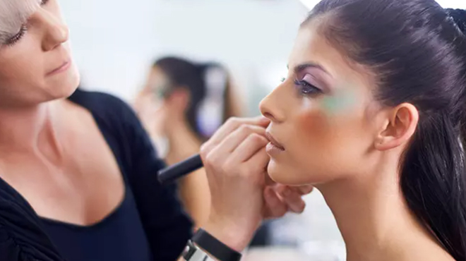 A makeup artist applying makeup on a lady