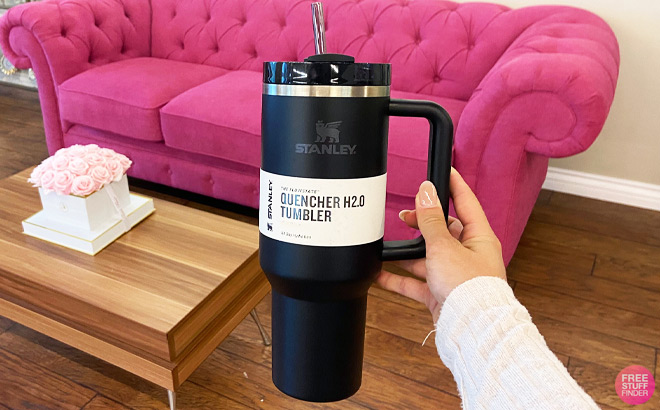 Hand Holding Black Stanley Quencher Flowstate Tumbler in front of a Pink Couch