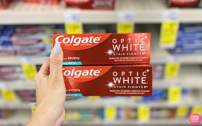 Hand Holding Two Colgate Optic White Stain Fighter Toothpaste