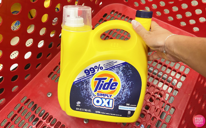 Hand Holding a Tide Simply Oxi Liquid Laundry Detergent in Cart