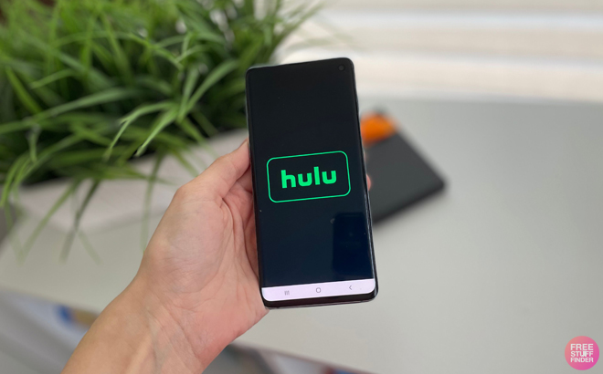 Hand Holding a Phone with Hulu on the Background