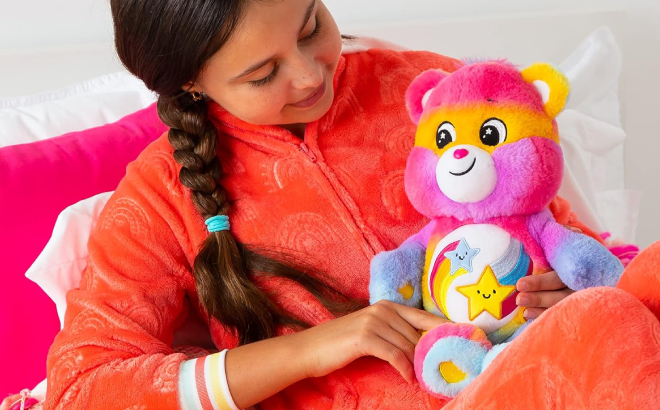 A Person Carrying a Care Bears Dare to Tie Dye 14 Inch Plush on Her Lap A Person Carrying a Care Bears Dare to Tie Dye 14 Inch Plush on Her Lap