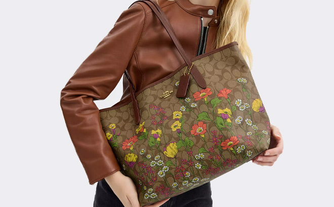 A Person Holding Coach Outlet City Tote In Signature Canvas With Floral Print