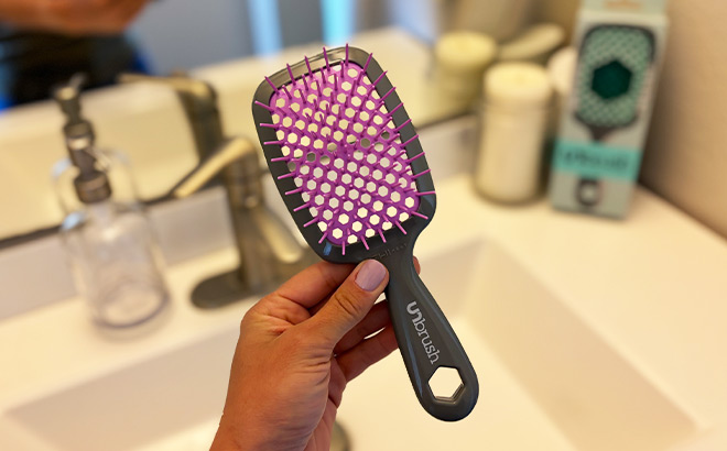 A Person Holding a Black and Pink Brush in the Bathroom