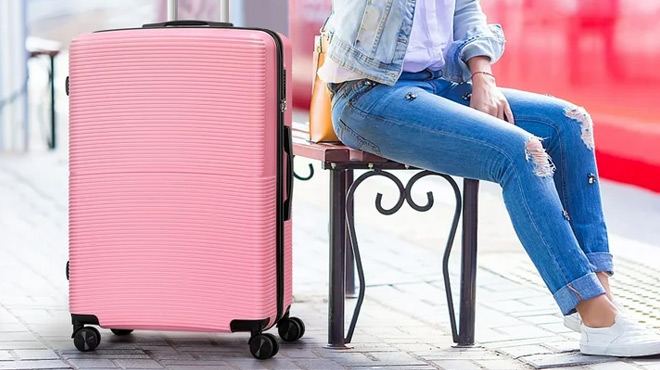 A Person Sitting on a Terminal Bench with a Pink Hikolaye Hardside Spinner on Her Side