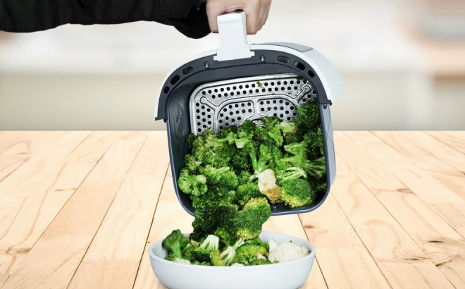 A Person Transferring Broccoli Cooked in Kalorik 5 Quart Air Fryer into a Bowl