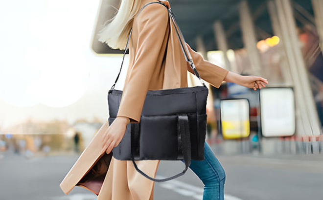 A Person Walking on The Street with a Travel Tote Bag in Black Color on Her Shoulder A Person Walking on The Street with a Travel Tote Bag in Black Color on Her Shoulder