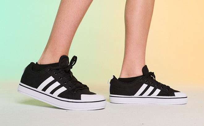 A Person Wearing Adidas Mens Bravada Athletic Shoes in Black Color