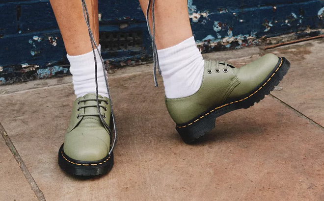 A Person Wearing Dr Martens Womens Virginia Leather Oxford Shoes in Muted Olive Color