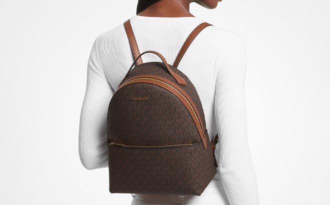 A Person Wearing Michael Kors Sheila Medium Logo Backpack in Brown Color