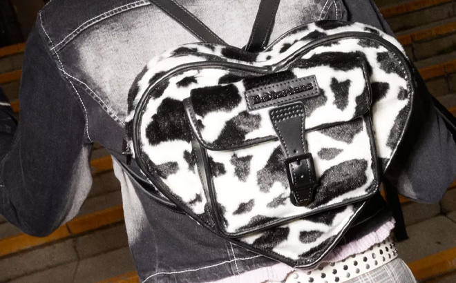 A Person is Wearing Dr Martens Heart Shaped Faux Fur Cow Print Backpack