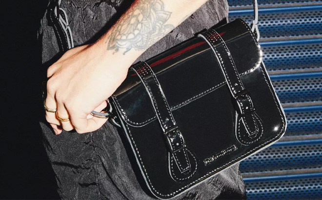 A Person is Wearing Dr Martens Patent Leather Crossbody Bag in Black Color