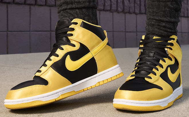 A Person is Wearing Nike Dunk High Womens Shoes in Black and Yellow Color