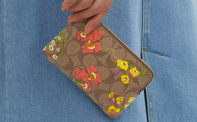 A Persong Holding Coach Outlet Corner Zip Wristlet In Signature Canvas With Floral Print