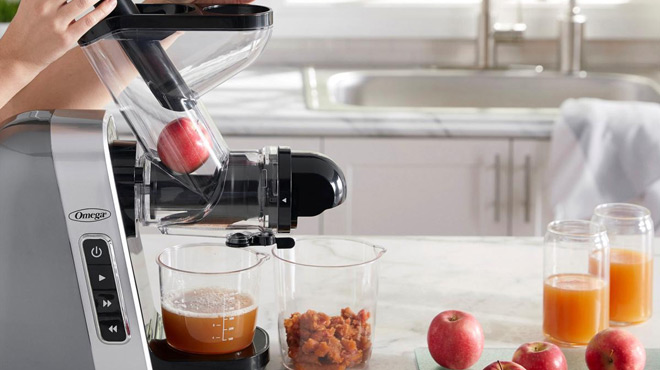 A Persons Hand Operating an Omega Slow Masticating Juice r 1 A Persons Hand Operating an Omega Slow Masticating Juice r 1