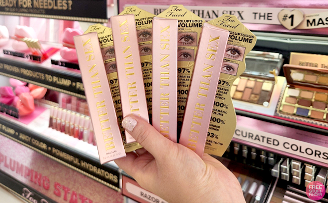 A Woman Holding 4 Packs of Too Faced Better Than Sex Mascara