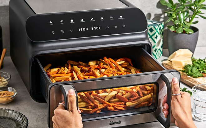 A Woman Opening the Basket of the Bella Pro Series 10.5-Quart Grill & Air Fryer A Woman Opening the Basket of the Bella Pro Series 10.5-Quart Grill & Air Fryer