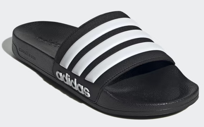 Adidas Adiletter Shower Slides in Black and White on a Gray Background