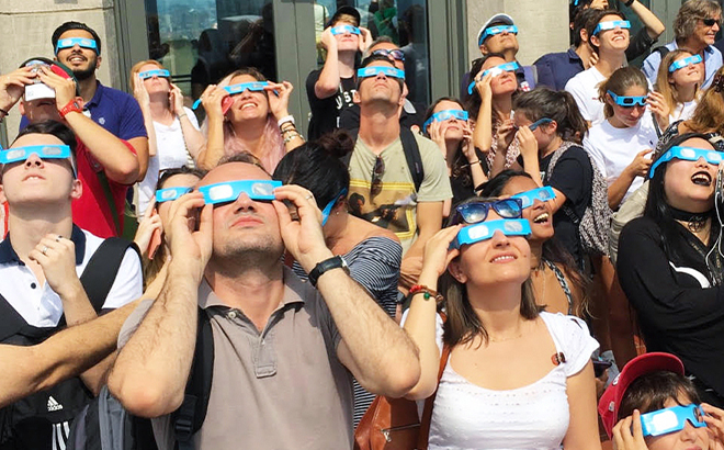 People Watching the Solar Eclipse with Warby Parker Free Solar Glasses in the Street