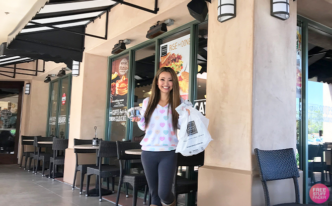 Tina Holding a Bag and a Dessert from Corner Bakery Cafe in Front of the Store