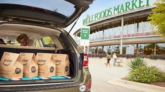 A Car Trunk Filled with Amazon Prime Grocery Bags with Whole Food Market on the background