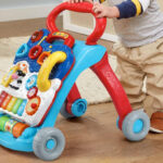 A Kid is Holding VTech Sit To Stand Learning Walker