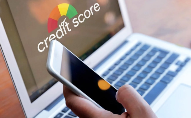 A Person Checking a Credit Score on a Laptop and Holding a Phone