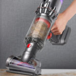 A Person Cleaning a Sofa using a Dyson Humdinger Cordless Handheld Vacuum