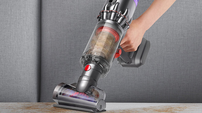 A Person Cleaning a Sofa using a Dyson Humdinger Cordless Handheld Vacuum