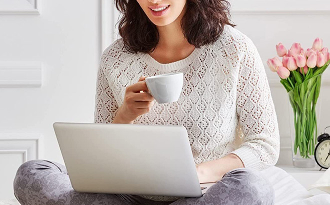 A Person Drinking Coffee and Typing on a Laptop