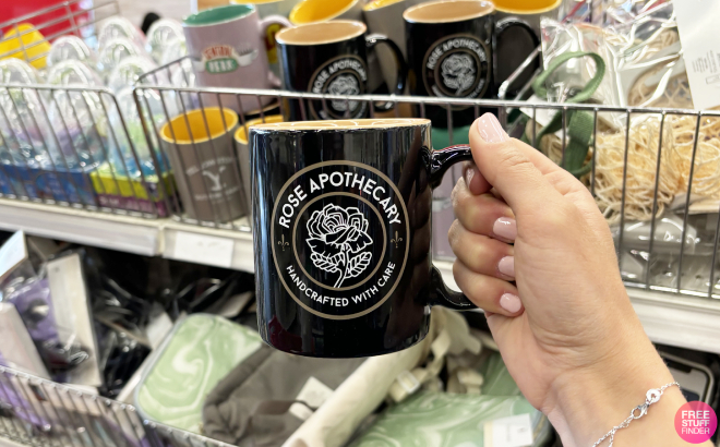 A Person Holding Schitts Greek Rose Apothecary Ceramic Mug