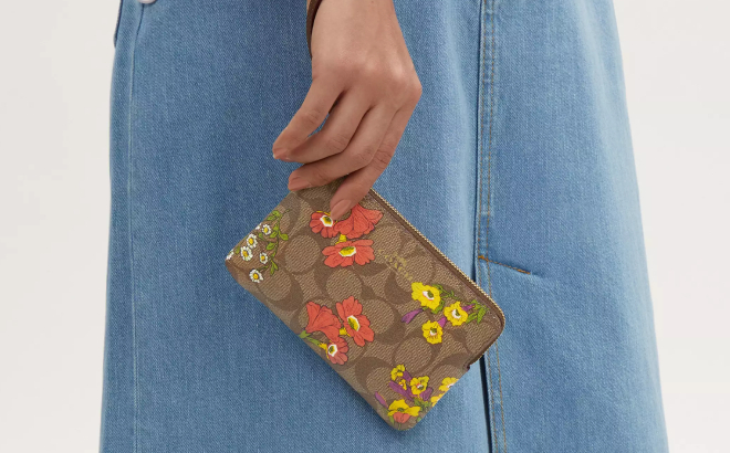 A Person Holding a Coach Outlet Corner Zip Wristlet In Signature Canvas With Floral Print