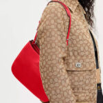 A Person Slinging a Coach Outlet Penelope Shoulder Bag In Bright Poppy Colors
