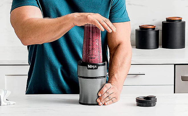 A Person Using the Ninja 20 Ounce Nutri Blender Plus on a Kitchen Counter