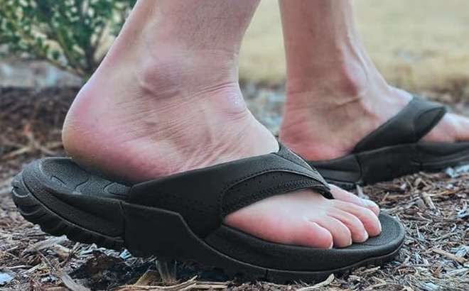 A Person Wearing a Pair of Airhas Mens Flip Flops in Black