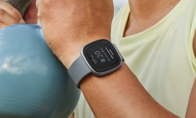 A Person Wearing the Fitbit Versa 4 Fitness Smartwatch in the Color Gray While Working Out