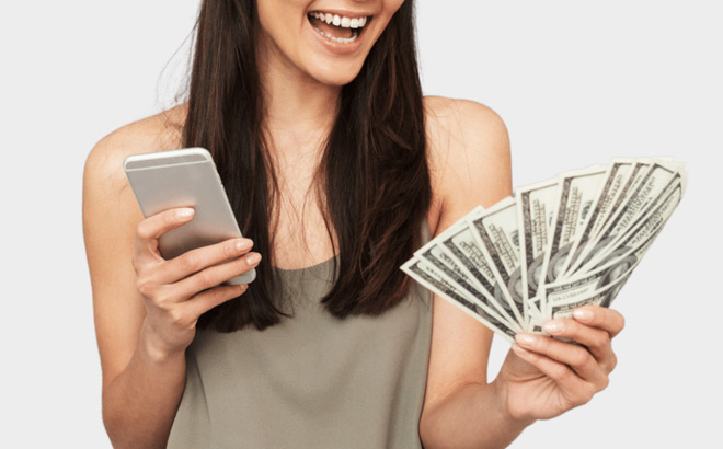 A Smiling Person Holding a Phone in One Hand and Cash in Other Hand