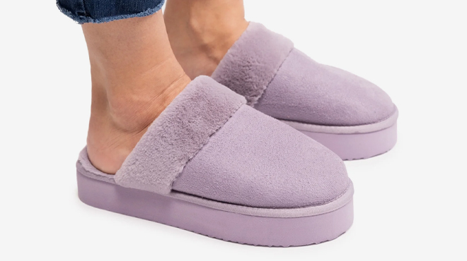 A person wearing a purple Muk Luks Womens Faux Fur Platform Scuff Slippers A photo of Muk Luks Womens Faux Fur Platform Scuff Slippers
