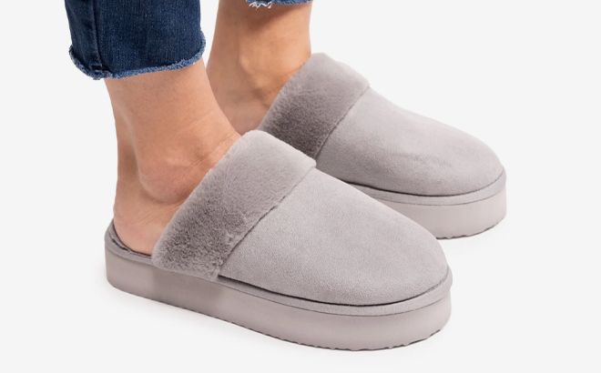 A person wearing a gray Muk Luks Womens Faux Fur Platform Scuff Slippers A photo showing Muk Luks Womens Faux Fur Platform Scuff Slippers