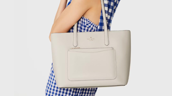 A photo showing a lady carrying a Kate Spade Staci Tote in Meringue color