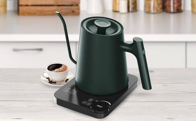Electric Kettle on a Table next to a Cup of Coffee