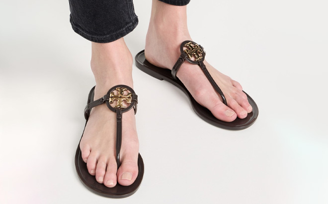 A Person Wearing Tory Burch Mini Miller Jelly Sandal in Coco Gold Color