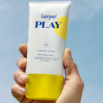 A Woman Holding Supergoop Play Everyday Lotion SPF 50 With Sunflower Extract
