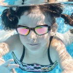 A Child Swiming in a Pool With Swimming Goggles