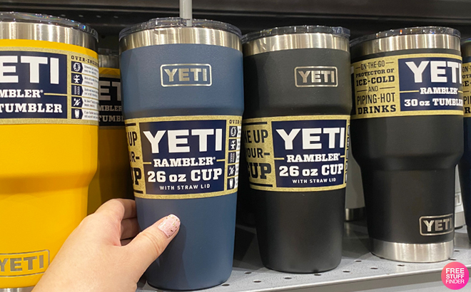 A Person Holding YETI Rambler 26 Ounce Straw Cup on a Shelf A Person Holding YETI Rambler 26 Ounce Straw Cup on a Shelf