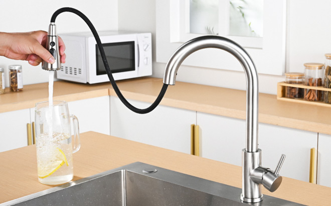 A Person Filling a Glass with Water by Using a Pull Down Faucet Sprayer A Person Filling a Glass with Water by Using a Pull Down Faucet Sprayer