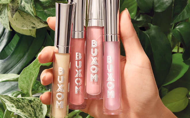 A Woman Holding Four Shades of Buxom Full On Plumping Lip Polish A Woman Holding Four Shades of Buxom Full On Plumping Lip Polish